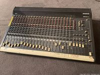 Front view of the Mackie SR24-4 audio mixer showing all 24 input channels with control knobs and fader sliders.