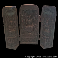 Front view of the shrine opened to show the carved Buddha figures surrounded by devotees in high relief on three hinged panels.