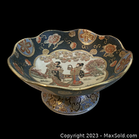 Side angle view of the footed bowl showing scalloped edges, colorful hand-painted geisha scene with gold trim, blue background with floral medallions.