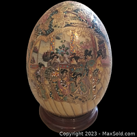 Front view of the Chinese Satsuma porcelain egg showing hand-painted detailed scene of Geisha women and moriage gold accents on wooden stand