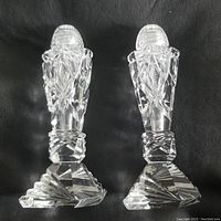 Pair of crystal salt and pepper shakers on black background showing entire items with their angular crystal bases and detailed cut design