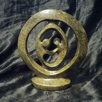 Front angle of the greenish polished stone Shona sculpture depicting two figures embraced inside a circular ring on a flat base.