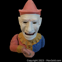 Front view of painted Humpty Dumpty clown mechanical bank showing face, hat, collar and arm position indicating coin slot.