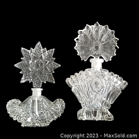 Pair of clear Imperial glass perfume bottles on black background showing intricate cut patterns on stoppers and bases.