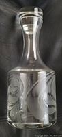 Clear Swedish-made Rosenthal crystal decanter with frosted raised swirl etching around the base, showing the overall shape and stopper on top.