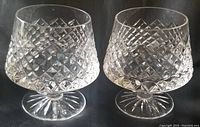 Pair of Tyrone Crystal cut crystal brandy snifter glasses with Sperrins pattern, shown from front on black background.