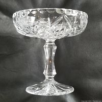 Side view of Waterford crystal compote showing the scalloped edge, diagonal leaf cuts on the bowl, and faceted stem with star-cut base.