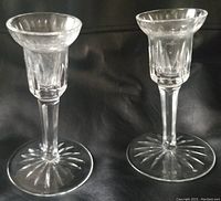 Pair of Waterford Crystal clear crystal candle holders, 5 inches tall, standing side by side on a black surface, showing their shape and starburst patterns on the bases.