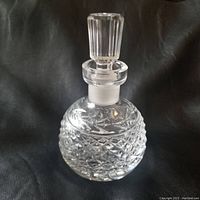 Front view of the Waterford Crystal Glandore round perfume bottle with attached ribbed stopper showing diamond and leaf cut patterns on the crystal body.