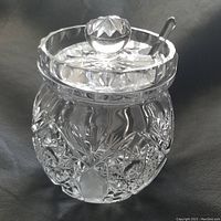 Clear intricately cut Waterford Crystal jar with lid and glass spoon inserted.