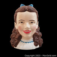 Front view of ceramic cookie jar shaped as Judy Garland's likeness as Dorothy, showing facial details and blue bow.