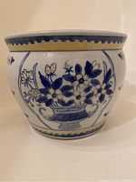 Side view showing detailed blue floral pattern with yellow border on ceramic planter.