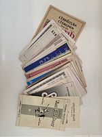 Photo showing a stack of approximately 40 pieces of choral sheet music and choir selections, fanned out to reveal partial titles and covers such as Christmas Choruses and others.