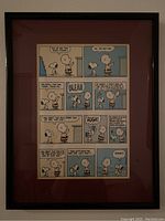 Framed Snoopy cartoon comic strip featuring Charlie Brown and Snoopy discussing books and bunnies within multiple colorful panels, housed in a black frame with maroon matte.