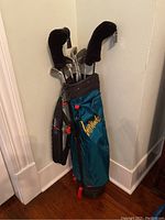 Full view of green Attitude Brunswick golf bag filled with golf clubs, showing carry strap and orange zipper pull.
