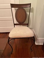 Metal, wood and fabric chair front view showing oval wood backrest panel and light fabric seat with stains.