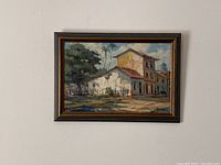 Framed oil painting on canvas of rustic urban scene hanging on wall