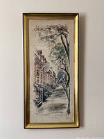 Full view of the framed vertical print showing the street and building scene with trees, inside glass has slight staining visible.