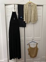 Full view of all clothing items hung on hangers: black halter dress, black pants, gold tank top, gold sequin jacket.