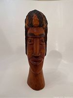 Front view showing detailed facial features and hair texture on the wooden bust sculpture.