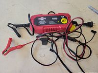 Full view of Motomaster battery charger with cables and clamps visible on work surface.