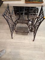 Front view of black cast iron Singer sewing machine base showing crossbar logo and legs