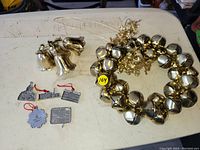 Photo showing the entire set on a white surface, including the bell wreath, cluster of three smaller bells, and four flat Kingston-themed metal ornaments with red hanging strings.