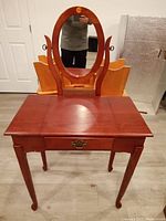 Front view of the wooden dressing table with oval mirror and drawer.