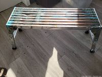Front top view of aluminum drywall bench showing slatted surface with paint splatters and wear marks.