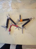 Three multi-tools laid out with tools extended showing pliers, knives, saw blades, and screwdrivers