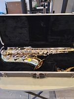 Open hard shell case containing disassembled silver-plated tenor saxophone parts