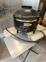 Front view of PizzaQue oven on table with paddle and hose