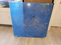 Front view of a 36x36 plexiglass sheet showing scratches and protecting film partially peeled.