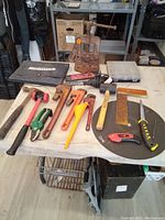 Tools laid out on table including hammer, mallet, pipe wrenches, pruning shears, funnel, utility knife, spirit level, cut-off disc, Mastercraft pouch