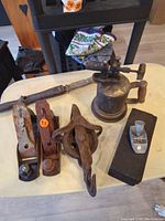 Overview of entire lot including all tools: three hand planes, nail puller, block and tackle, wet stone, and brass blow torch