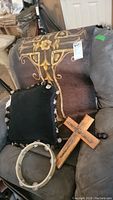 Set including religious tapestry on metal rods, wooden cross with nail details, tambourine, and decorative pillow.