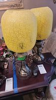 Pair of matching lamps with yellow crazed glass shades on a wooden table.