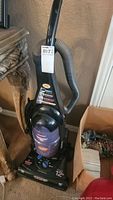 Upright Dirt Devil Quick Power vacuum cleaner with hose attached, black and purple color.