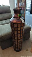 Tall decorative floor vase with dark brown and copper tones and a textured square grid pattern on the body.