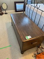 Front and top view of dark brown wooden chest on carpet, caster feet visible