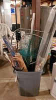 Large plastic container filled with various fishing equipment including nets, rods, umbrella, and rolled mat