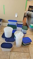 Overall view of assorted Tupperware containers with blue, green lids and a tall cylindrical container with handle