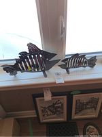 Two metal fish sculptures displayed on a window sill under natural light, showing overall size and appearance.