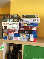 Stack of fourteen puzzle boxes showing brands, piece count and some artwork