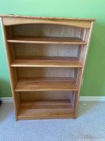 Front view of the solid wood bookcase shelf showing four shelves and curved top detail.