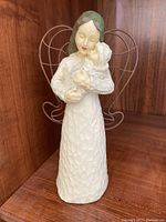 Front view of Willow Tree figurine with woman holding baby, detailed textured carving and painted features.