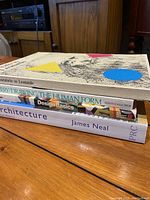 Stack of four art books viewed from the side, titles visible including Laboratorio su Leonardo, Figure Drawing The Human Form, Design Basics, Architecture by James Neal.