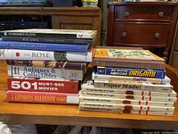 Photo showing a large stack of art, craft, collectibles, and reference books including a five-volume Encyclopedia of Crafts, DC Super Heroes Origami book, and others.