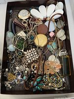 Tray filled with mixed necklaces, bracelets, rings, brooches and earrings