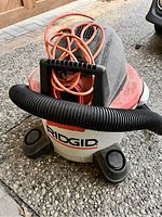 Ridgid wet/dry vacuum cleaner showing brand label, orange cord, missing hose